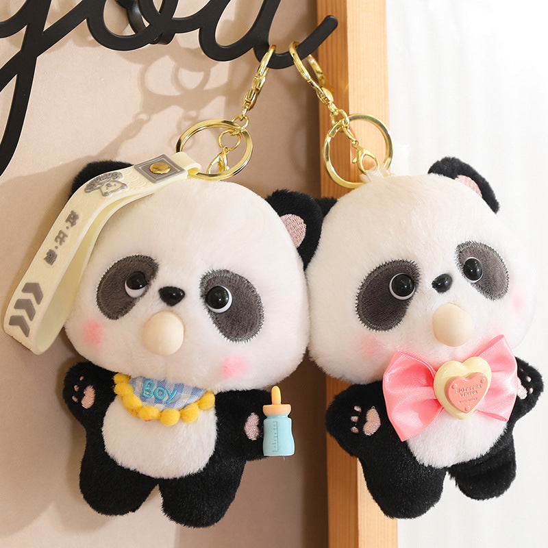 Two panda plush keychains with accessories on a wooden surface.