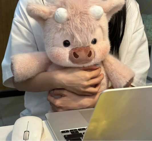 Person holding a plush pig toy in front of a laptop