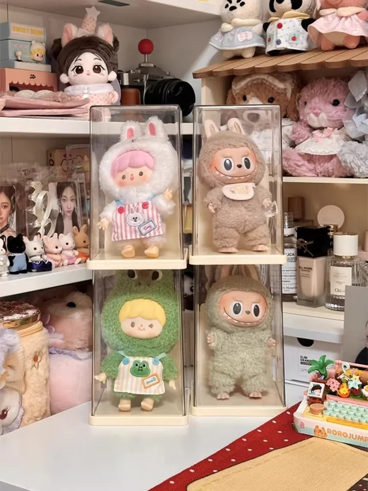 Collection of small figurines in clear display cases on a shelf with various items in the background.