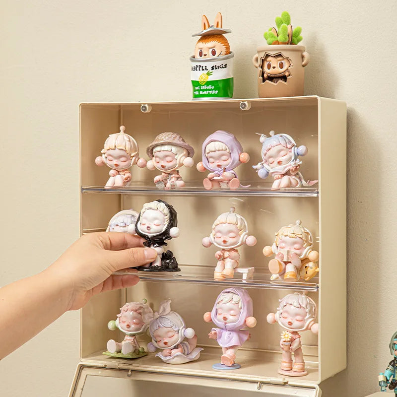 Collection of small figurines on a display shelf with a hand reaching out to pick one up.
