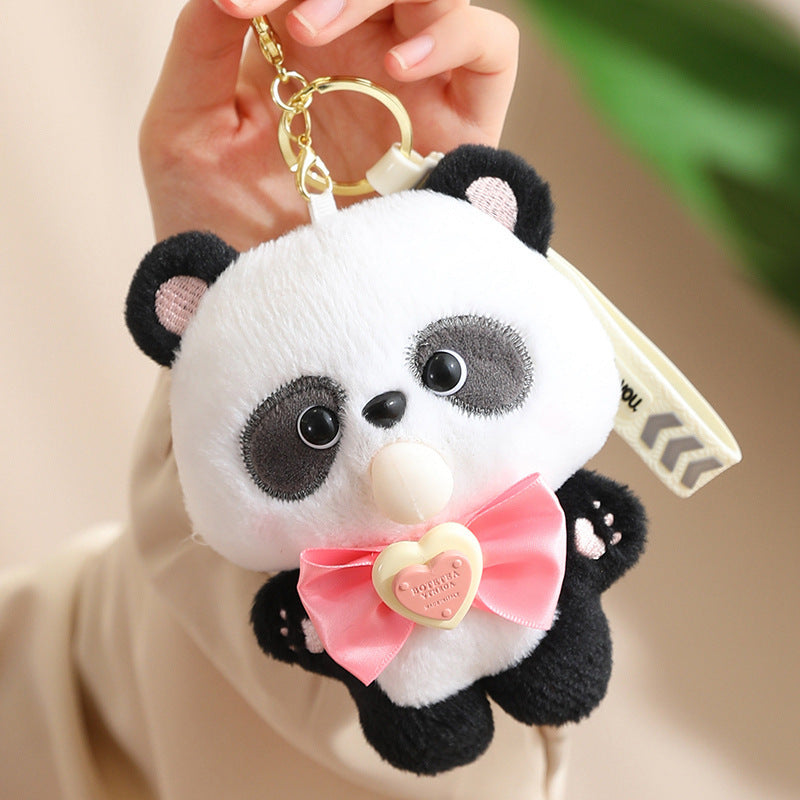 Plush panda keychain with a pink bow held by a hand against a neutral background