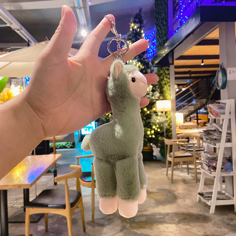 Hand holding a plush llama keychain in a restaurant setting