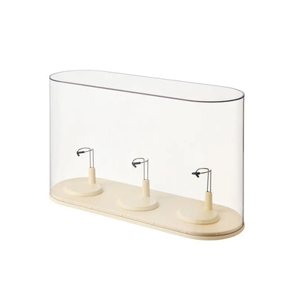 Clear glass display case with three white cylindrical objects on a white background