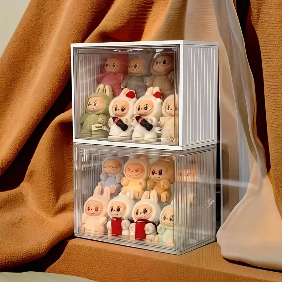 Stack of clear acrylic toy display cases with small figurines on a textured surface.